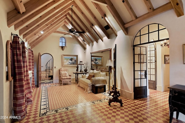 living area featuring beam ceiling, high vaulted ceiling, and ceiling fan with notable chandelier