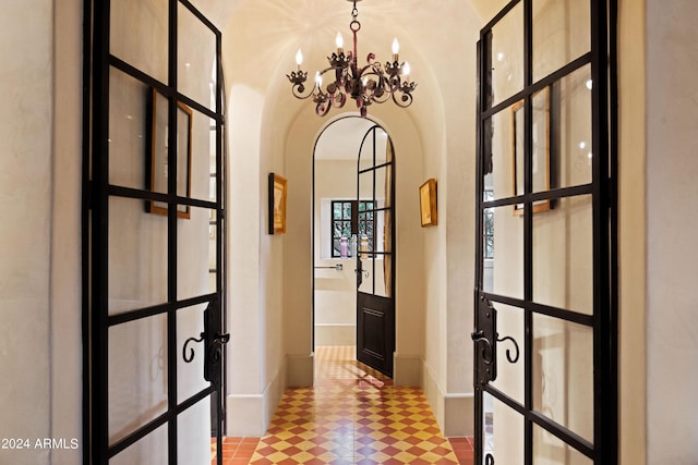 corridor with a notable chandelier, baseboards, and arched walkways