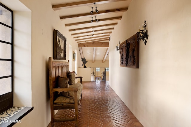 hallway featuring beamed ceiling and brick floor