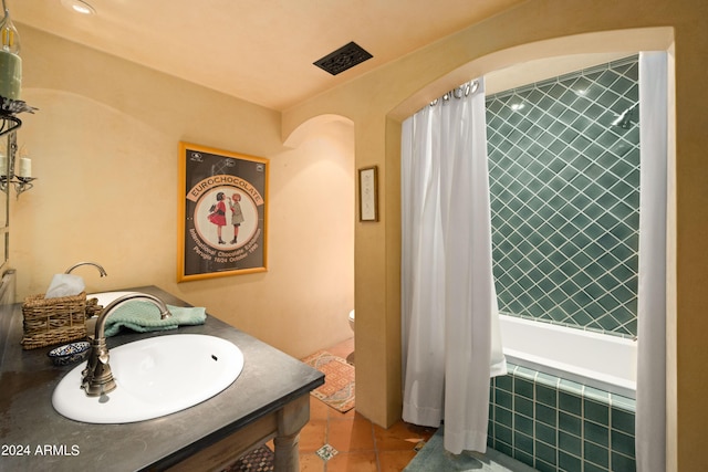 full bath featuring tile patterned floors, toilet, tiled shower / bath combo, and a sink