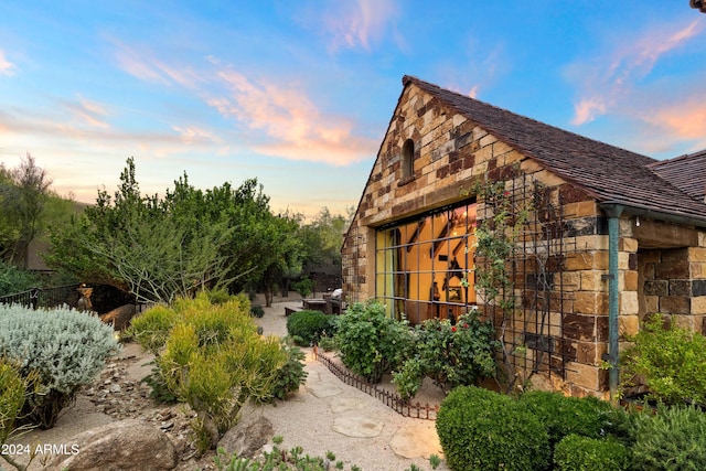 property exterior at dusk featuring stone siding