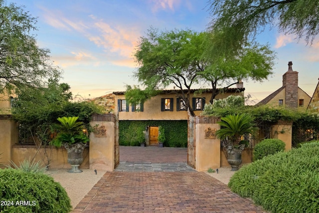 gate at dusk featuring a fenced front yard