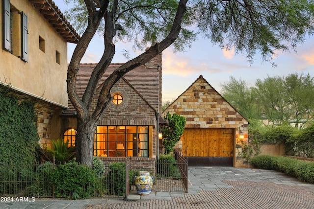 view of front of property with stucco siding, a garage, brick siding, and fence