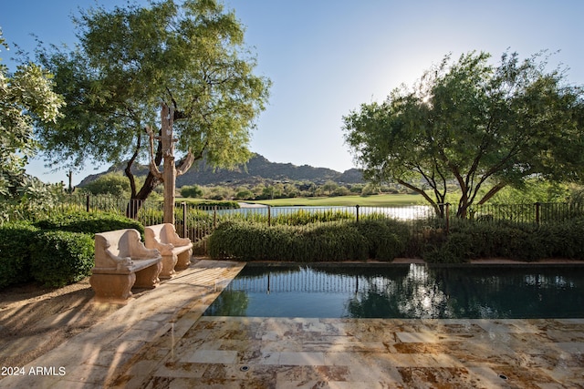 view of swimming pool featuring fence and a water and mountain view