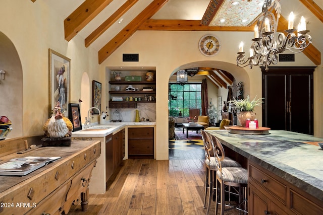 kitchen featuring a sink, beam ceiling, arched walkways, and an inviting chandelier