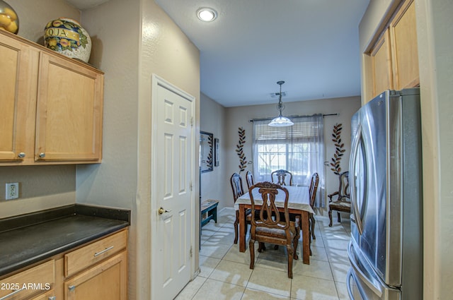 kitchen featuring light tile patterned flooring, stainless steel fridge, and hanging light fixtures