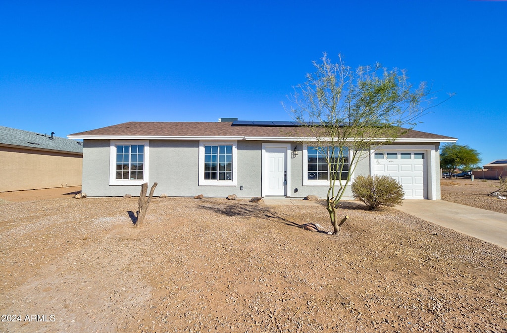 ranch-style home with a garage and solar panels