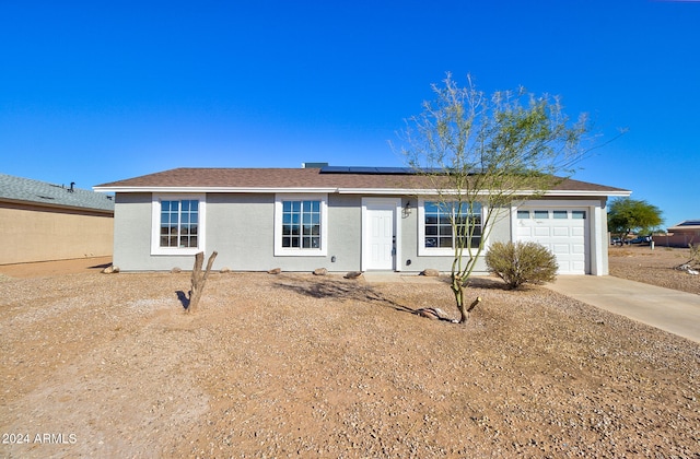 ranch-style home with a garage and solar panels