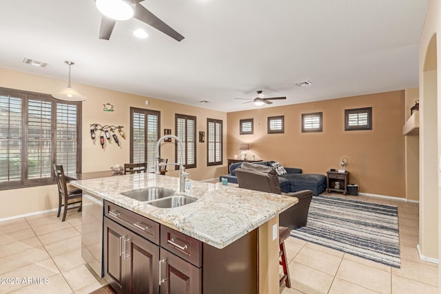 16259 W Papago St, Goodyear, AZ 85338 - kitchen featuring a ceiling fan, light tile patterned flooring, hanging light fixtures, light stone counters, and dark brown cabinets