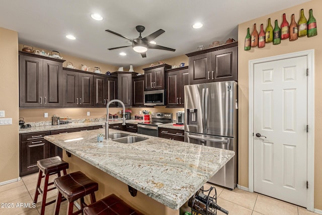 16259 W Papago St, Goodyear, AZ 85338 - kitchen with stainless steel appliances, a kitchen breakfast bar, light tile patterned floors, a ceiling fan, and dark brown cabinets