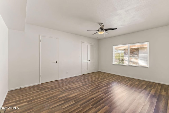 unfurnished bedroom with multiple closets, dark wood-type flooring, a textured ceiling, and ceiling fan