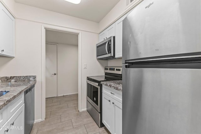 kitchen with stainless steel appliances, white cabinets, and stone counters