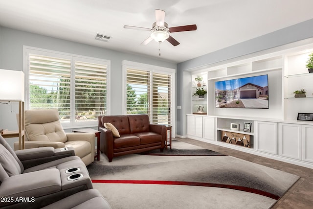 living area with ceiling fan, healthy amount of natural light, and built in shelves