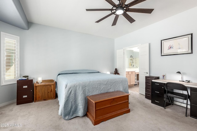 bedroom with light carpet, an office area, connected bathroom, and a ceiling fan