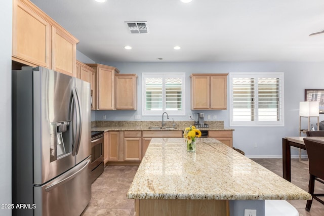 kitchen featuring appliances with stainless steel finishes, light brown cabinets, a sink, light stone counters, and recessed lighting