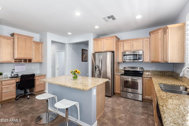 kitchen with appliances with stainless steel finishes, a sink, light brown cabinetry, light stone counters, and recessed lighting