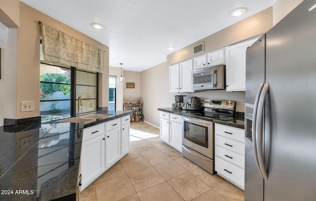 kitchen with white cabinets, sink, appliances with stainless steel finishes, decorative light fixtures, and light tile patterned flooring