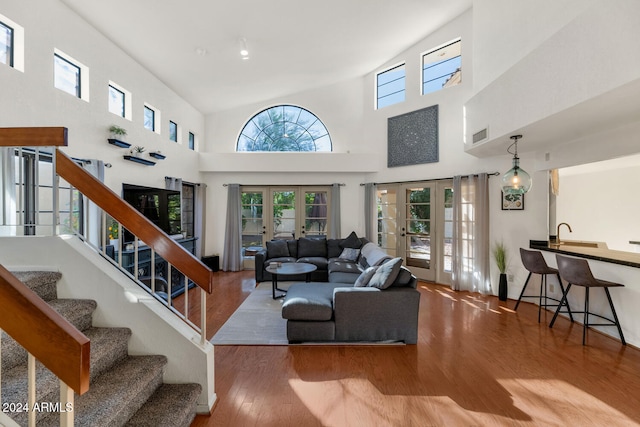 living room with hardwood / wood-style floors, high vaulted ceiling, and french doors