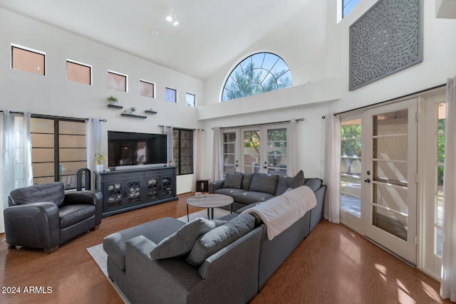 living room with hardwood / wood-style flooring, high vaulted ceiling, and french doors