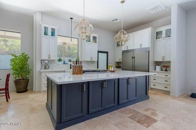 kitchen featuring stainless steel appliances, pendant lighting, white cabinets, and tasteful backsplash