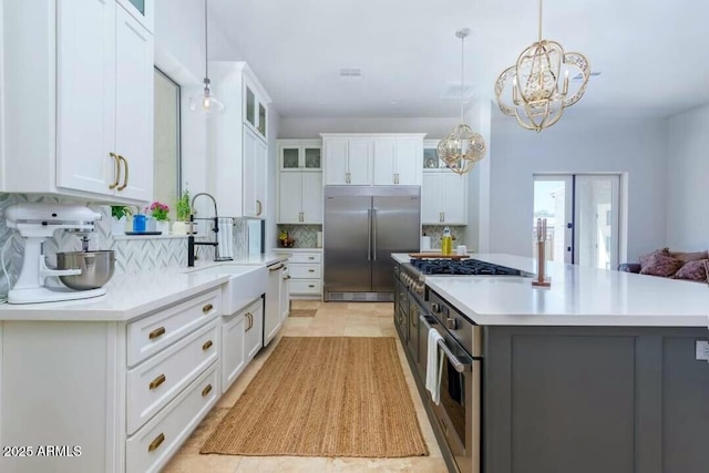 kitchen with hanging light fixtures, backsplash, appliances with stainless steel finishes, and white cabinetry