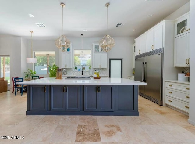 kitchen featuring backsplash, a center island, pendant lighting, white cabinets, and built in fridge