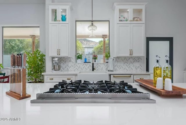 kitchen featuring decorative backsplash, sink, white cabinetry, and pendant lighting