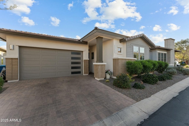 view of front of property featuring decorative driveway, an attached garage, and stucco siding