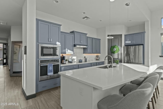 kitchen featuring visible vents, a sink, stainless steel appliances, light countertops, and tasteful backsplash