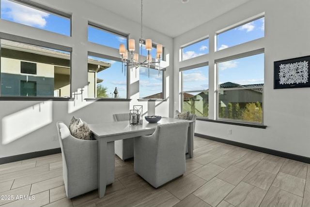 dining room featuring a notable chandelier, baseboards, and wood tiled floor