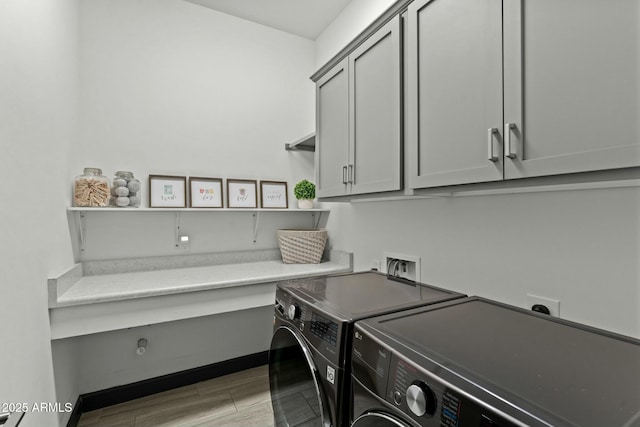 washroom featuring washer and clothes dryer, cabinet space, light wood-style flooring, and baseboards