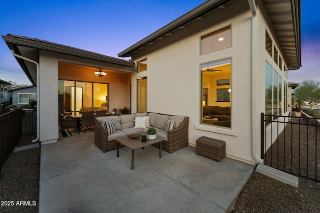 patio terrace at dusk featuring outdoor lounge area and fence