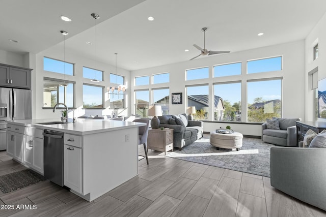 kitchen with open floor plan, stainless steel appliances, light countertops, and a sink