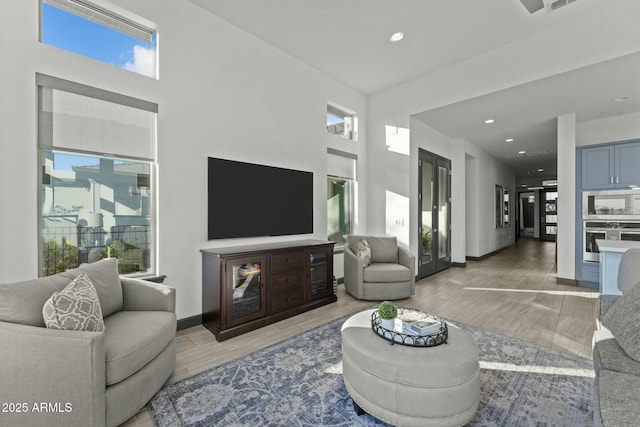 living room featuring recessed lighting, baseboards, plenty of natural light, and light wood finished floors