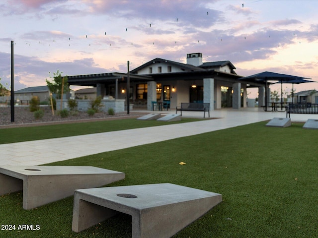 back house at dusk featuring a lawn