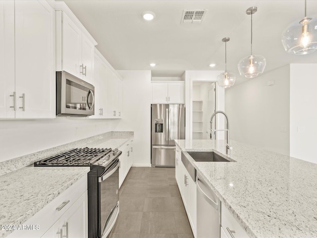 kitchen with white cabinets, sink, decorative light fixtures, light stone counters, and stainless steel appliances