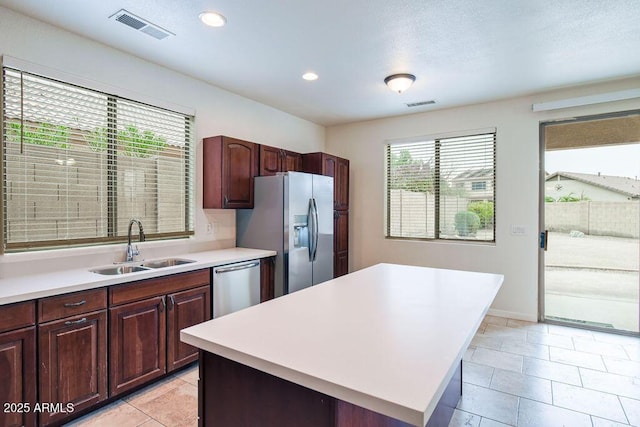 kitchen with sink, light tile patterned floors, appliances with stainless steel finishes, and a kitchen island