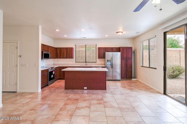 kitchen featuring a kitchen island, appliances with stainless steel finishes, sink, light tile patterned floors, and ceiling fan