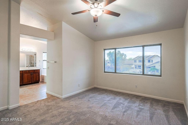 empty room with vaulted ceiling, ceiling fan, sink, and light carpet