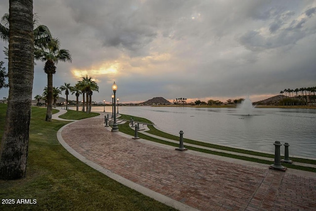 surrounding community with a water view and a lawn