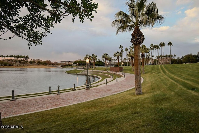 view of property's community with a water view and a lawn