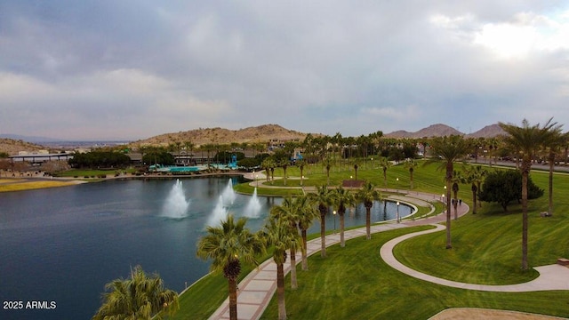 view of property's community with a water and mountain view and a lawn