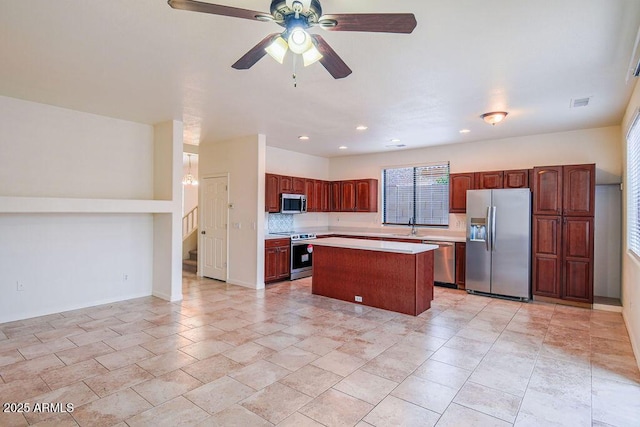 kitchen with sink, ceiling fan, stainless steel appliances, a center island, and tasteful backsplash