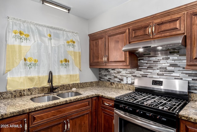 6837 W Camelback Rd, Phoenix, AZ 85033 - kitchen with stainless steel gas stove, a sink, under cabinet range hood, light stone counters, and decorative backsplash