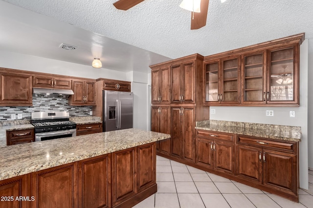 6837 W Camelback Rd, Phoenix, AZ 85033 - kitchen with stainless steel appliances, under cabinet range hood, a ceiling fan, light tile patterned floors, and glass insert cabinets