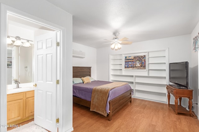 bedroom featuring ceiling fan, sink, light hardwood / wood-style flooring, and a wall mounted AC