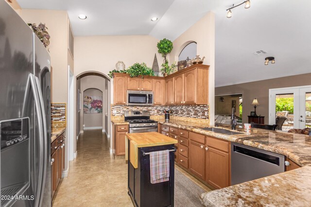 kitchen featuring ceiling fan, light tile patterned flooring, kitchen peninsula, lofted ceiling, and stainless steel appliances