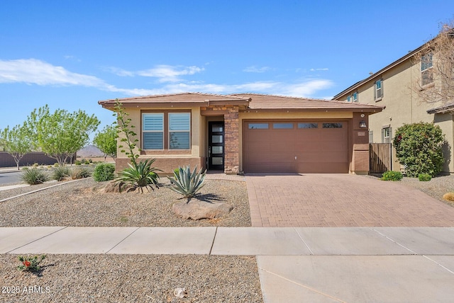 prairie-style house featuring stucco siding, an attached garage, and decorative driveway