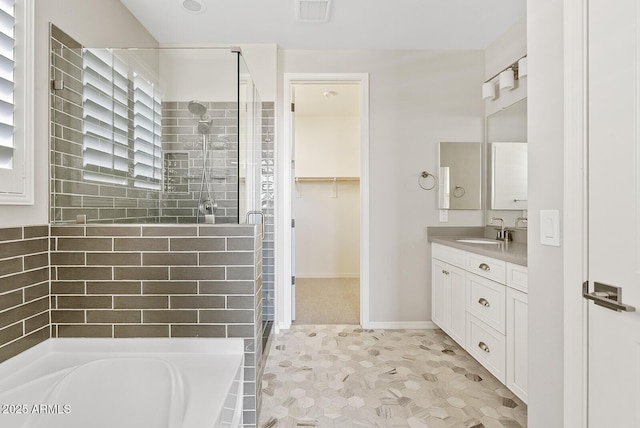 full bathroom featuring visible vents, a garden tub, a shower stall, a spacious closet, and vanity