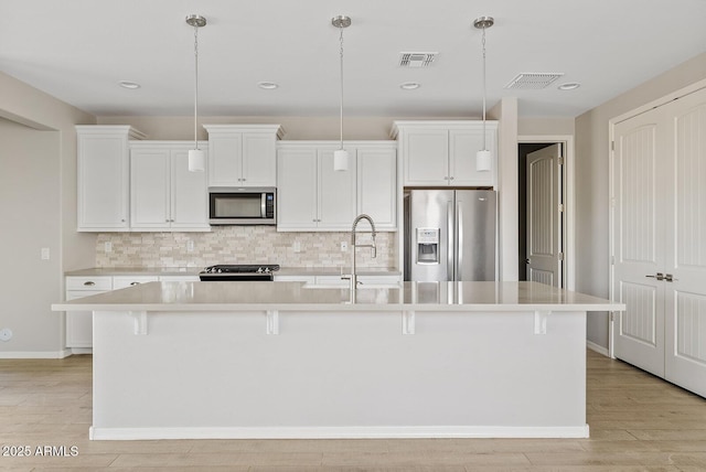 kitchen with a sink, a kitchen island with sink, visible vents, and stainless steel appliances